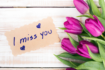 words I MISS YOU and bouquet of tulips on wooden background