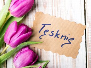 Polish words I MISS YOU and bouquet of tulips on wooden background