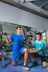 sport, fitness, teamwork, bodybuilding people concept - man and personal trainer with barbell flexing muscles in gym