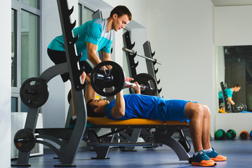 Young Man In Gym Exercising Chest On The Bench Press with barbell