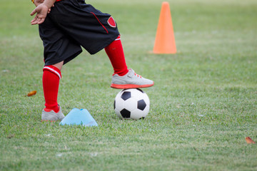 Little boy in black shorts and trainers with his foot on top of