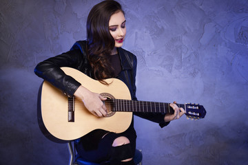 Young teenage girl playing on guitar.