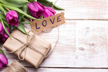 word LOVE and bouquet of tulips on wooden background