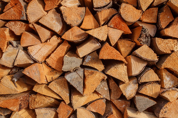 Background of dry chopped firewood logs stacked up on top of eac