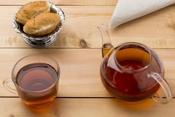 Set of glass tea cup and  little teapot with croissant