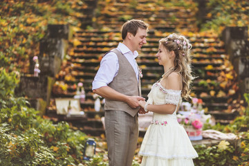 Stylish Loving wedding couple stand near the stone steps surrounded by rustic decoration
