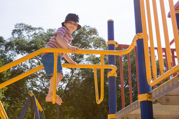 Young boy playing outside on climbing frame