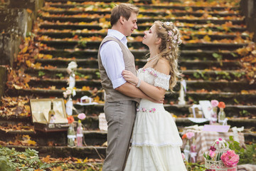 Wedding couple in a rustic style hugging near the stone steps surrounded by wedding decor