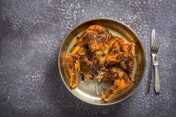 Fried chicken on a tray. Chicken tobacco or chicken tapaka. Georgian cuisine. Fork and knife. Copy space on a background