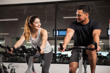 Cute young couple flirting at a gym while cycling