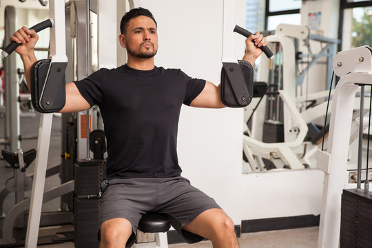 Handsome man on a pec deck machine