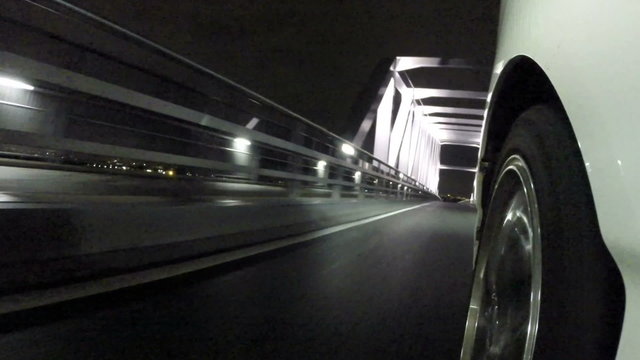 Front wheel variation of a car running through the nightscape of Tokyo's Gate Bridge.