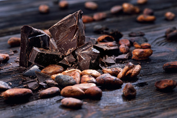 Chocolate pieces with cocoa beans on a wooden table