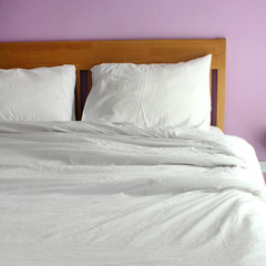 white bed with light purple wall in the morning