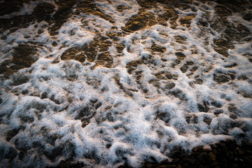 Waves at the seashore at sunset. Selective focus with shallow depth of field.
