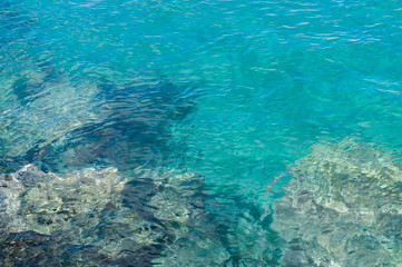 Naklejka na ściany i meble Transparent turquoise water near rocky coast