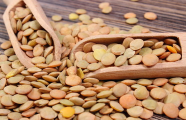 Heap of green lentil with spoon on wooden background