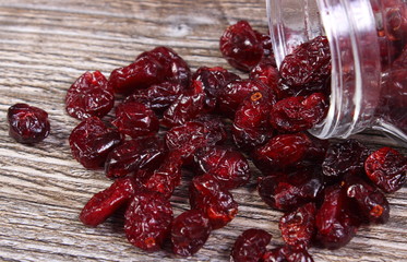 Cranberries spilling out of glass jar on wooden table