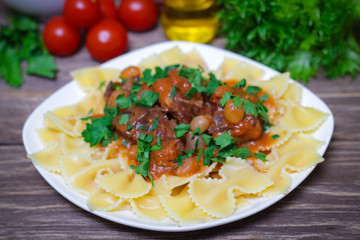 National Greek dish of pasta with stifado (beef, tomato and onions, stewed in red wine with herbs) on a wooden background, horizontal