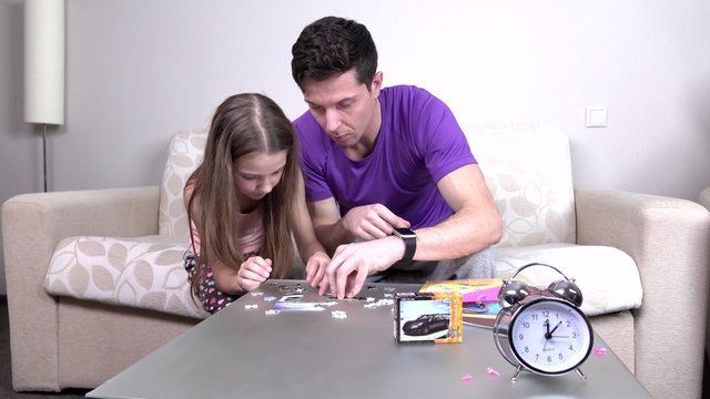 Father and daughter playing with puzzle on the table