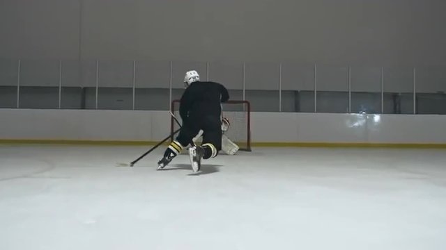 Follow shot of forward hockey player skating towards the net and trying to score the goal but goaltender preventing it 