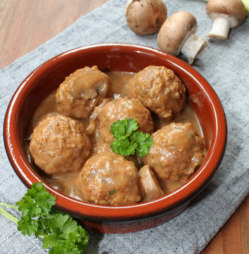 Fleischkl&ouml;sschen in Champignon-Rahmsauce mit Petersilie garniert auf  grauem Tischtuch