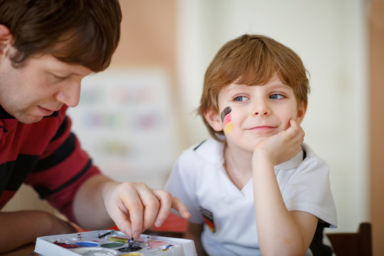 Father painting flag on face of little kid for football or socce