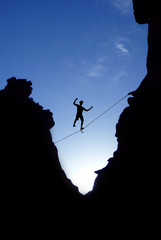 Man walking on tight rope over the rock