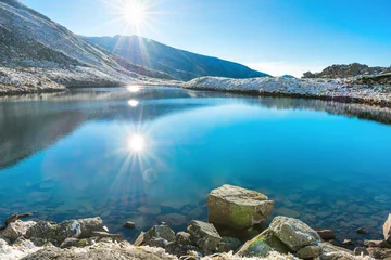 Foto op Plexiglas Meer Beautiful blue lake in the mountains, sunset time. Landscape with sun and reflection in water