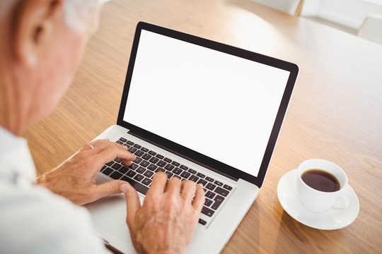 Focused elderly man typing on laptop