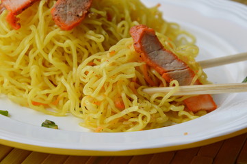 egg noodle with barbecue pork picking by wooden chopstick