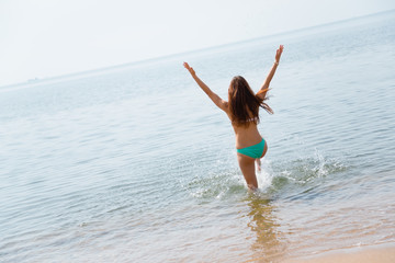 Happy young woman runs into the sea