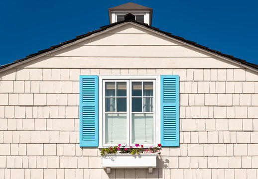 white wooden facade with blue shutters and flowers