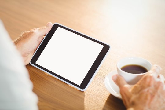 Elderly Man Using Tablet And Drinking Coffee