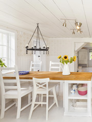 lantligt kök med köksbord, vedspis och en vas med solrosor