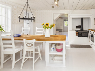 lantligt kök med köksbord, vedspis och en vas med solrosor