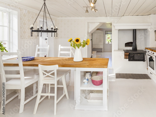 Lantligt kök med köksbord, vedspis och en vas med solrosor stock ...