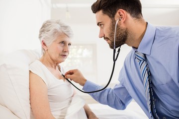 Home nurse listening to chest of patient with stethoscope