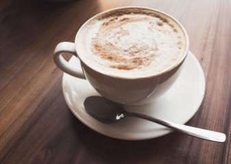  Cup of coffee with milk stands on wooden table