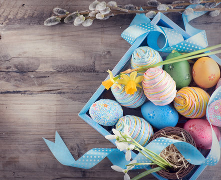 Easter concept. Colorful blue eggs and spring snowdrop flowers over wooden background