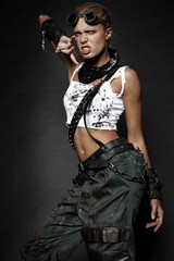 Young woman in brutal style clothes with goggles on studio black background