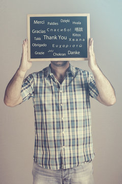 Man expressing his gratitude holding a Thank You message board written in many different languages