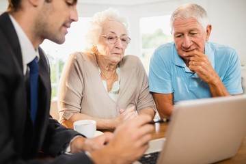 Obraz premium Businessman showing laptop to senior couple