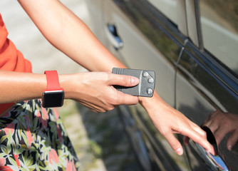 women's hand with smart watch presses on the remote control car alarm systems