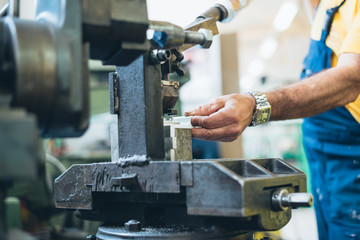 Close up photo of dirty workers hand doing some job on big metalworking machine. Selective focus.