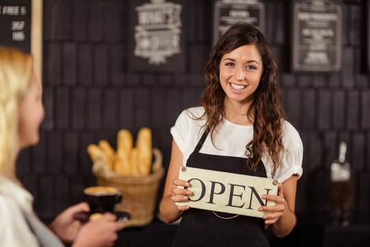 Portrait of a waitress showing open sign 