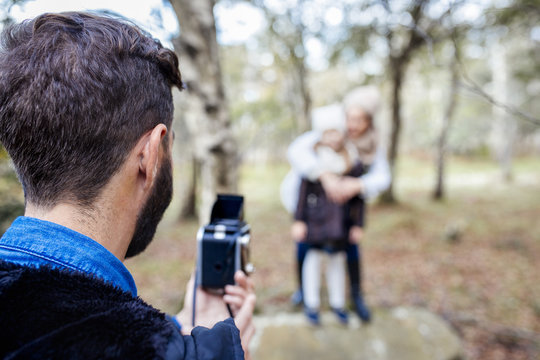 Father taking picture of wife and daughter in the forest