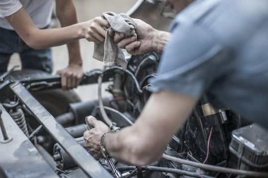 Grandfather and grandson restoring a car together