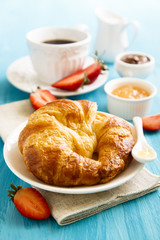 Breakfast table with croissant, marmalade and coffee