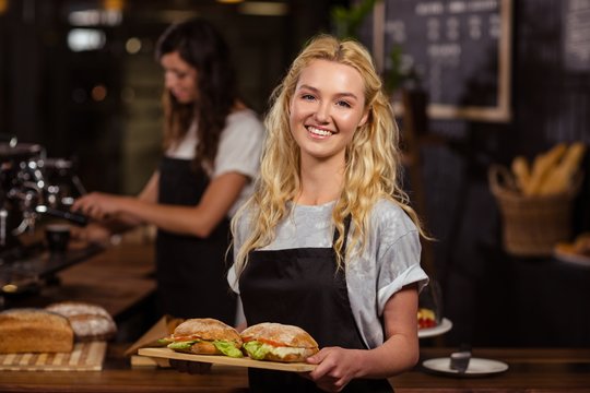 Pretty waitress holding a tray with sandwiches 